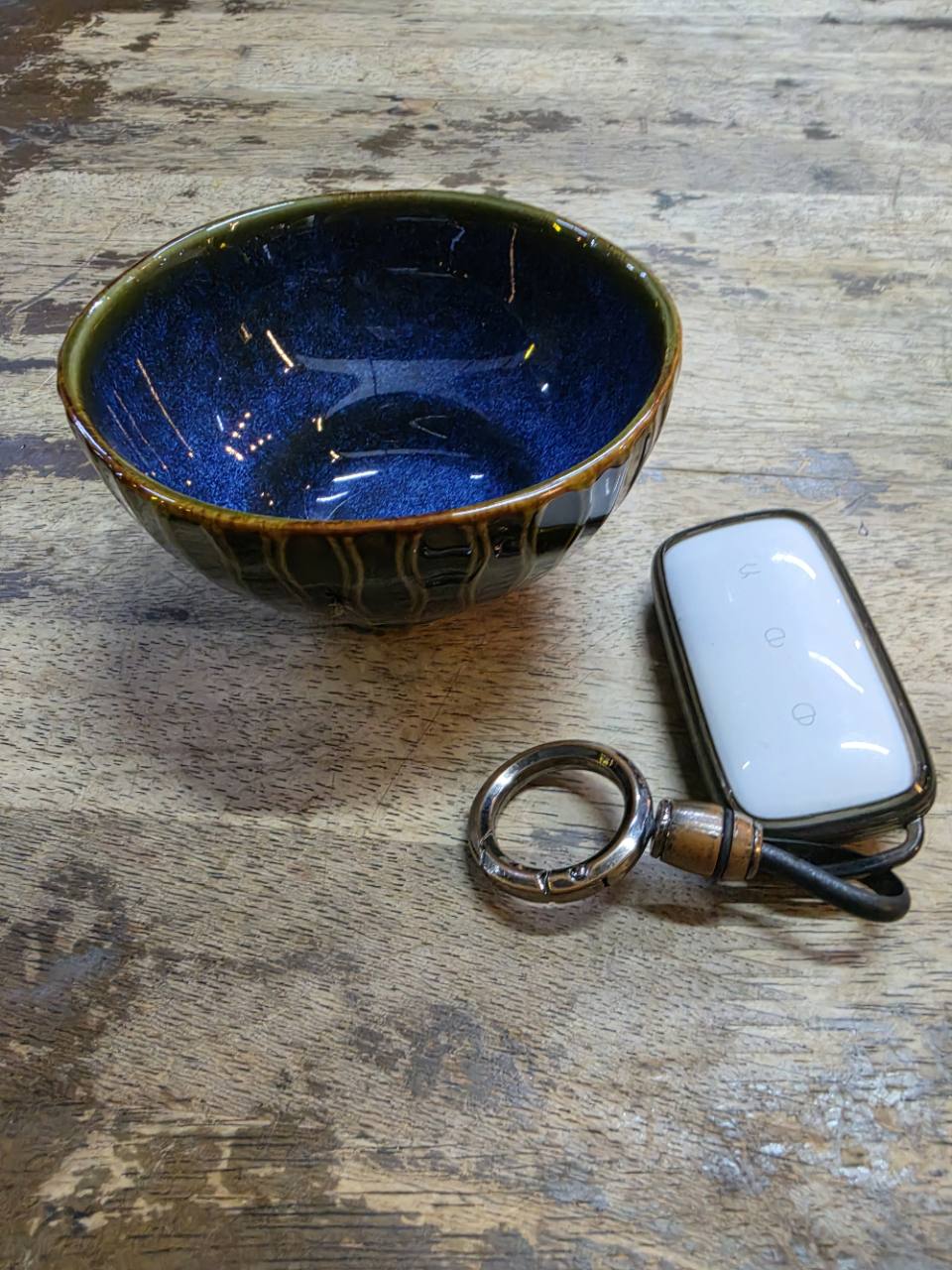 A deep-blue glazed bowl and an e.MAS 7 Premium key resting on a worn wooden warung table in Kota Damansara at 00:19 on 2 September 2026.
